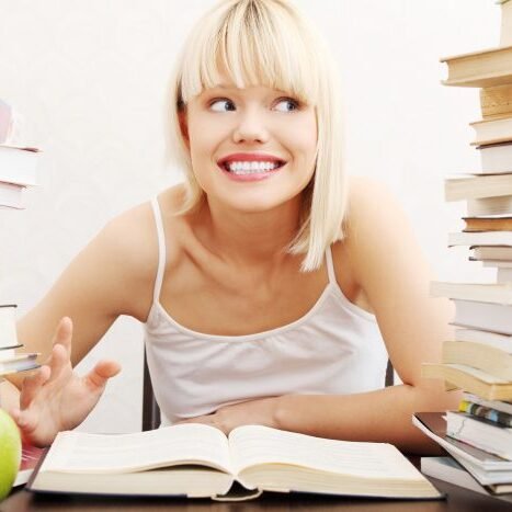 Young student woman with lots of books studying for exams. 